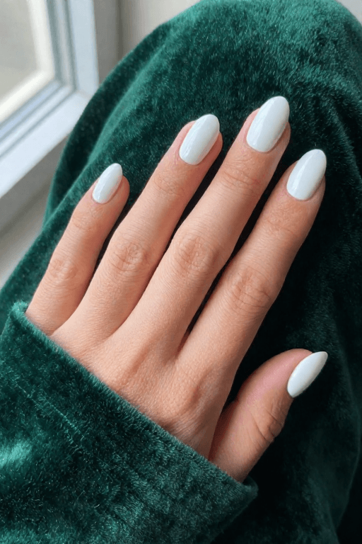 Short almond nails painted in solid bright white with a glossy finish