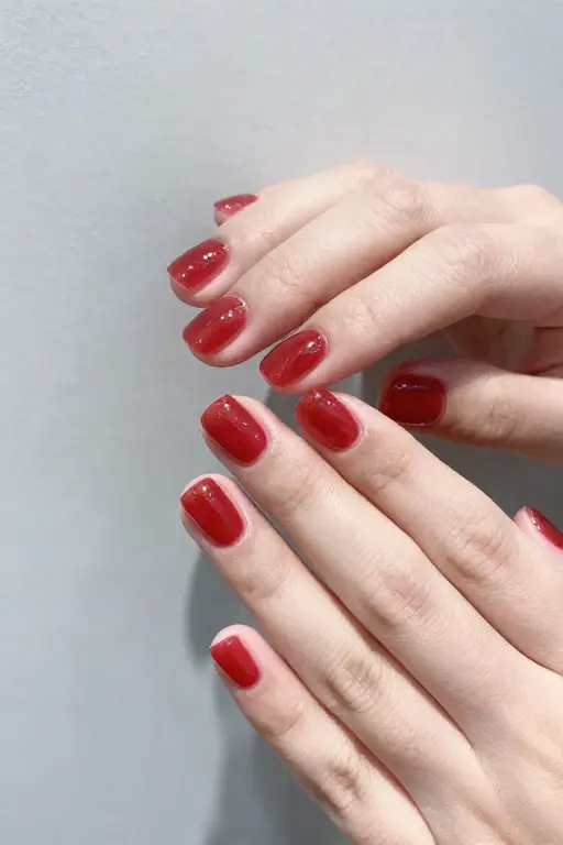 Garnet Jelly Short rounded garnet jelly nails with translucent cherry red polish.