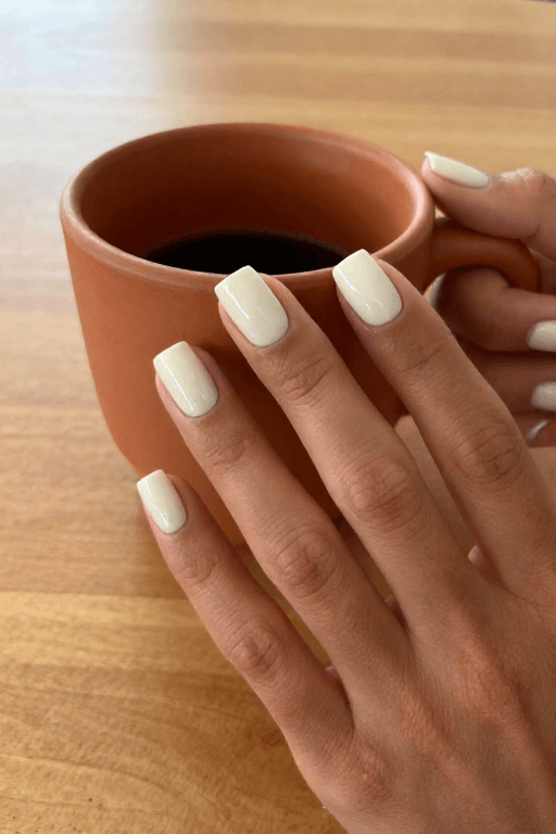Square nails in warm off-white polish, close up