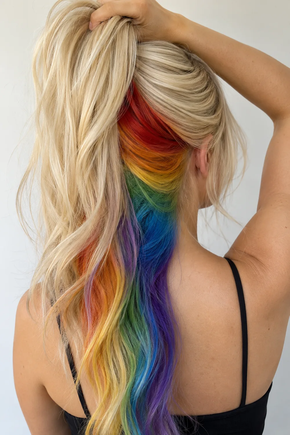 Rainbow peekaboo hair color under a blonde top layer